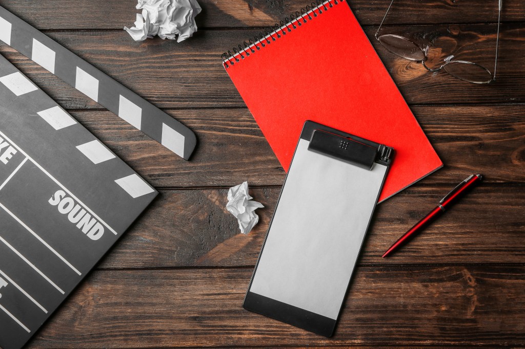 Composition with movie clapper, clipboard and notebook on wooden background, top view